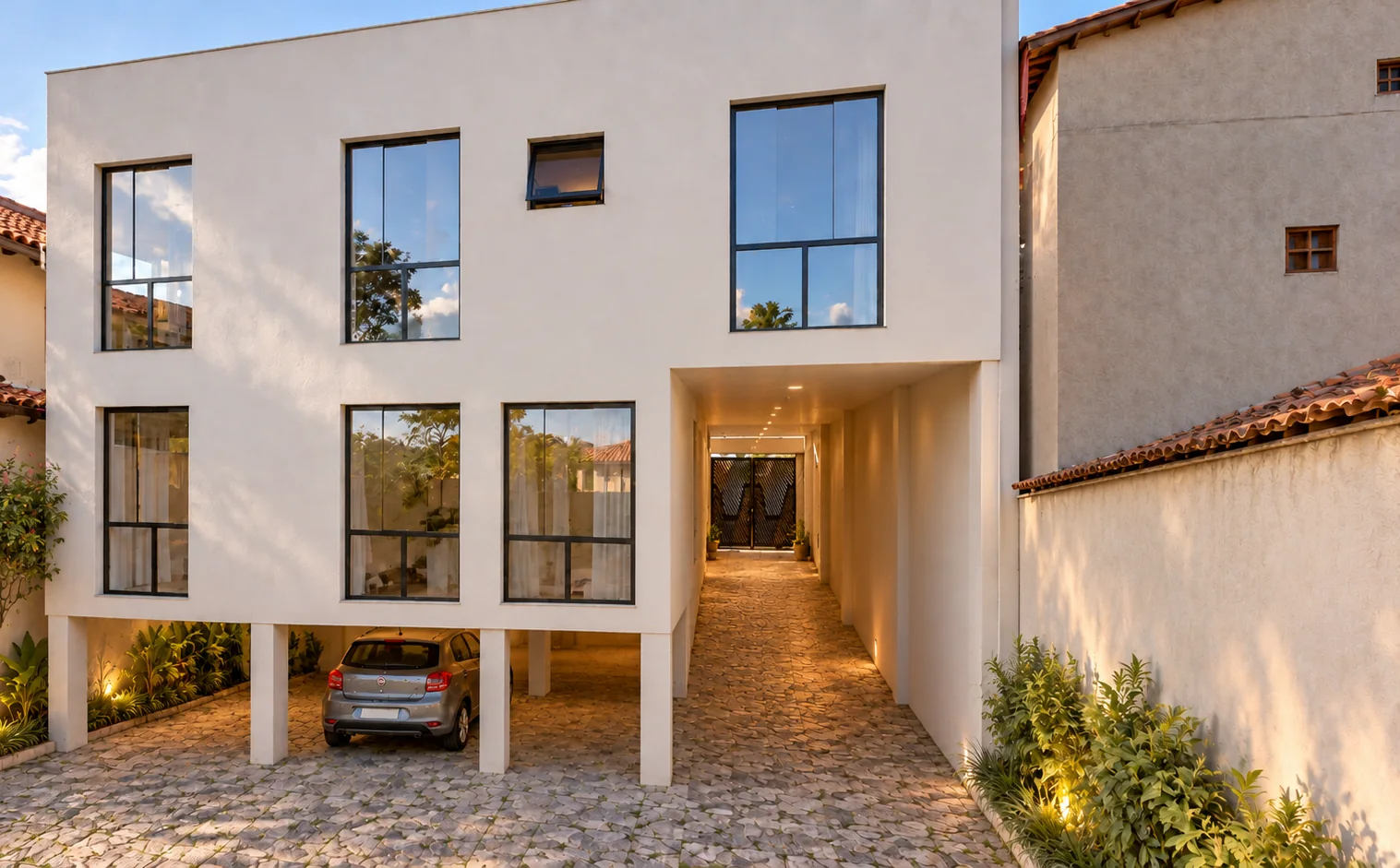 Rückfassade mit Garage unter Stützen und beleuchtetem Seitengang
