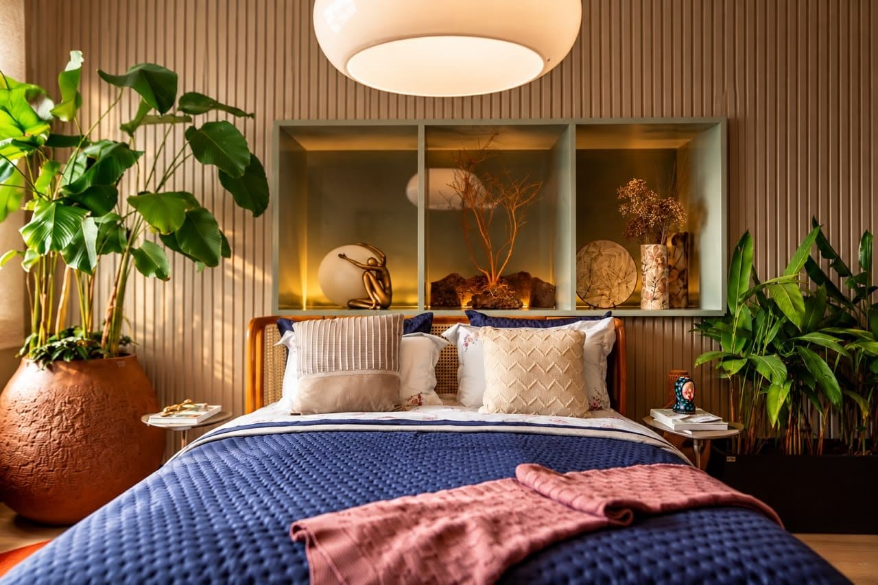 Quarto do Paisagista: cama com colcha azul, plantas e luz natural